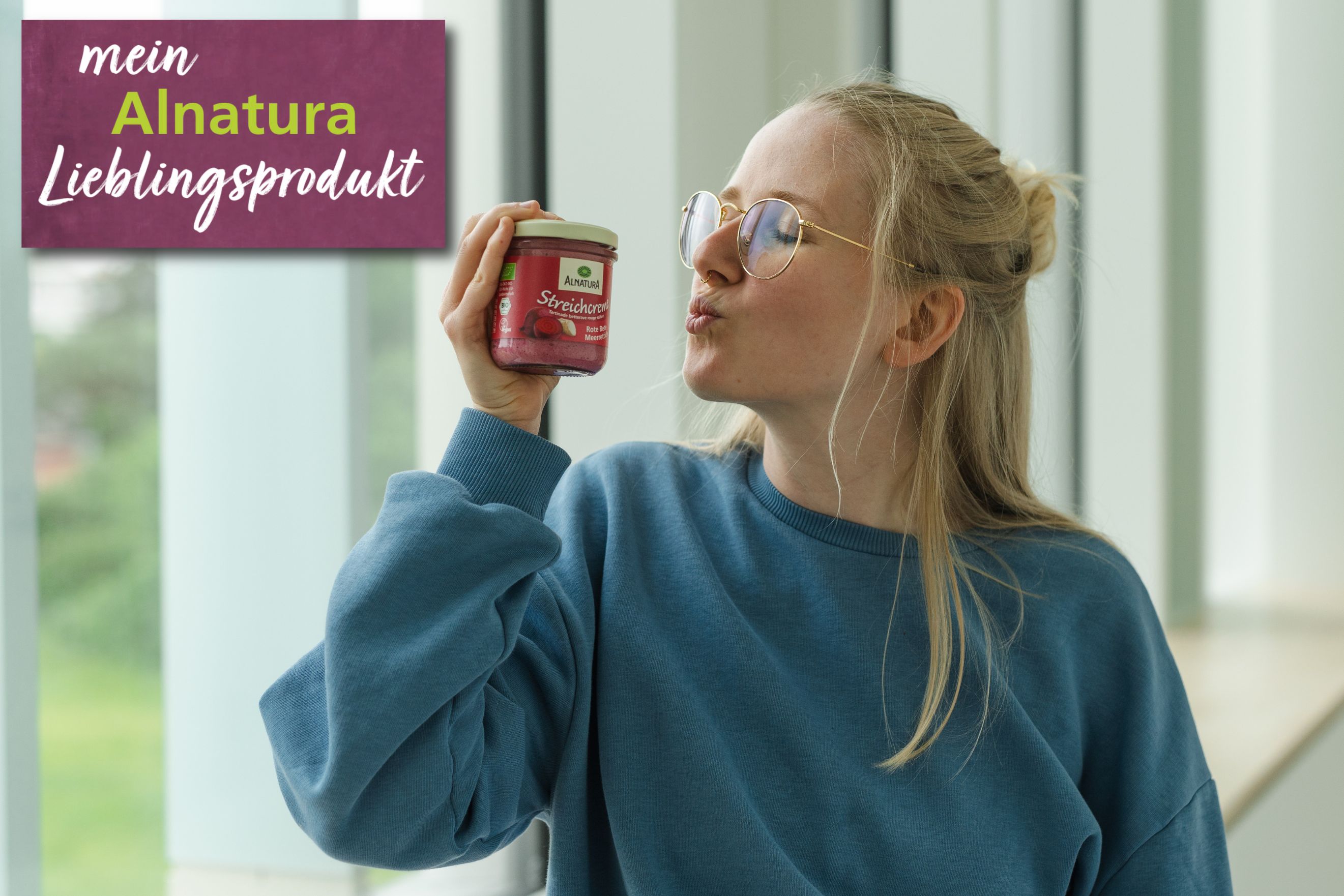 Alnatura Kundin Mila hält ihr Alnatura Lieblingsprodukt Streichcreme Rote-Bete-Meerrettich in die Kamera.