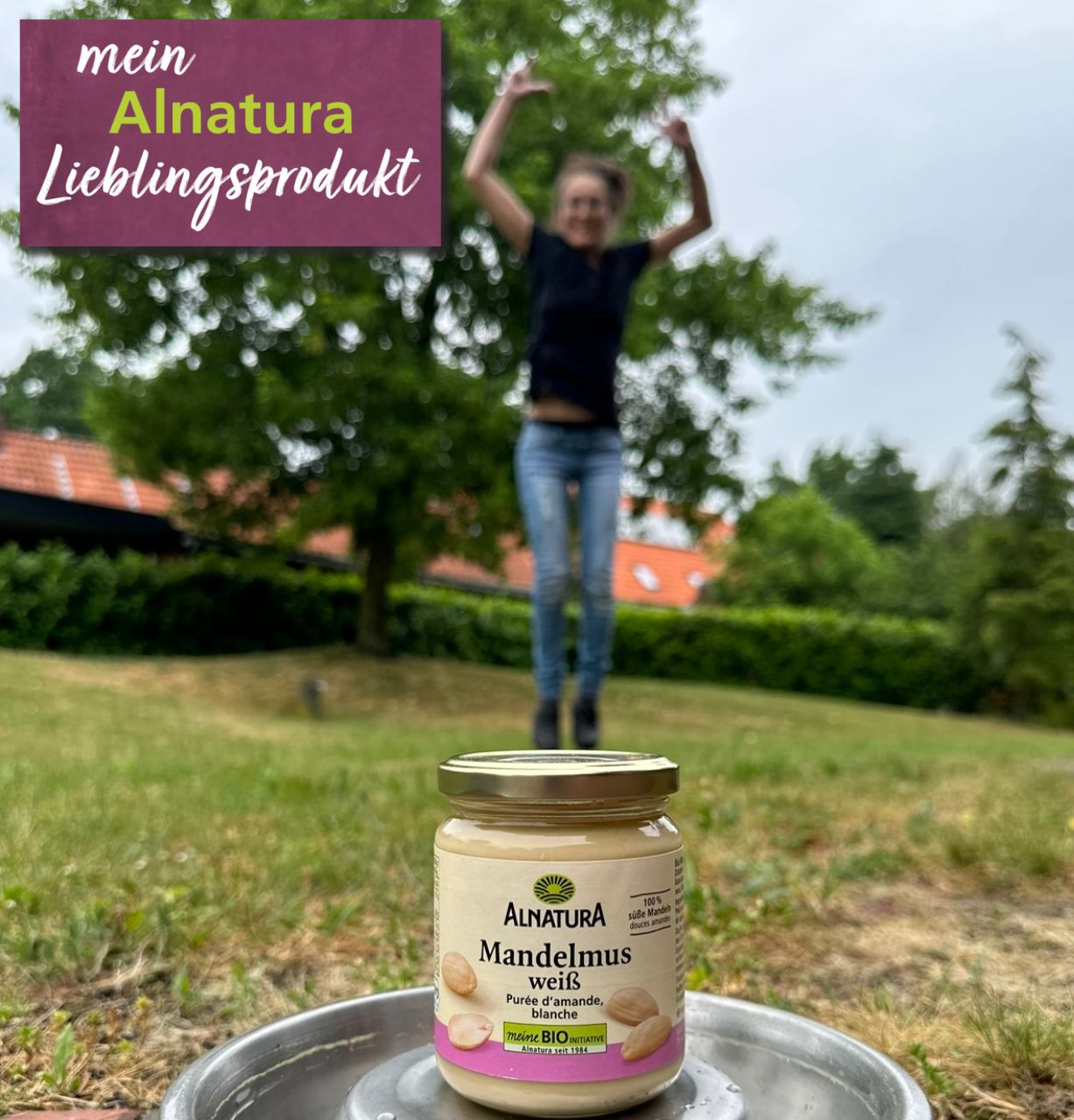 Alnatura Kundin Nicole springt im Bildhintergrund, so dass der Eindruck entsteht, sie stehe auf ihrem Alnatura Lieblingsprodukt Mandelmus weiß.