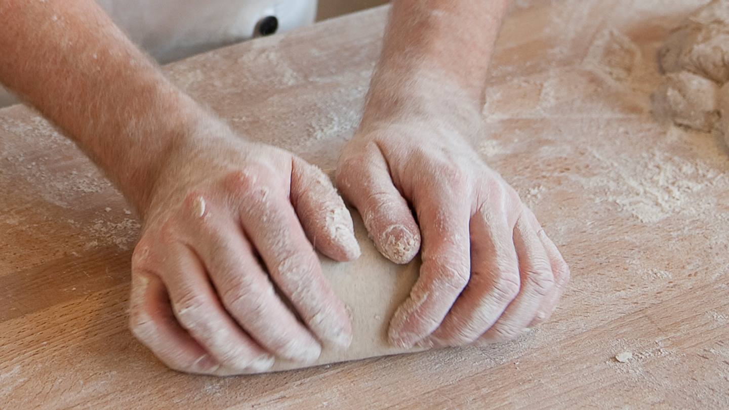 Ein Stück Teig wird von einem Bäcker geknetet