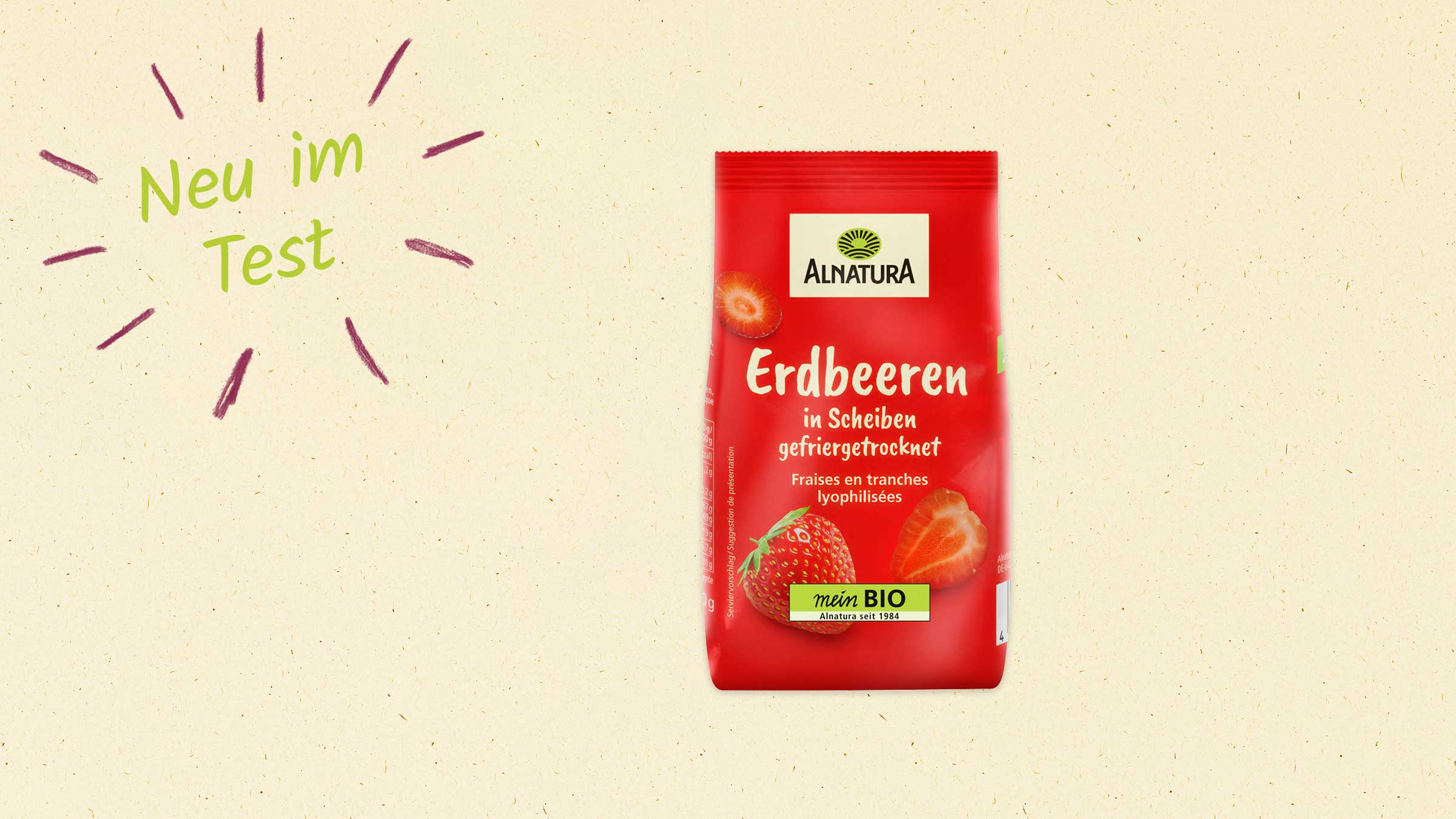 Ein rotes Päckchen gefriergetrocknete Erdbeerscheiben der Marke Alnatura ist auf einem hellen Hintergrund zu sehen. Auf dem Päckchen sind zwei Erdbeeren abgebildet, eine ganze Frucht und eine halbe. Oben links steht in grüner Schrift "Neu im Test".