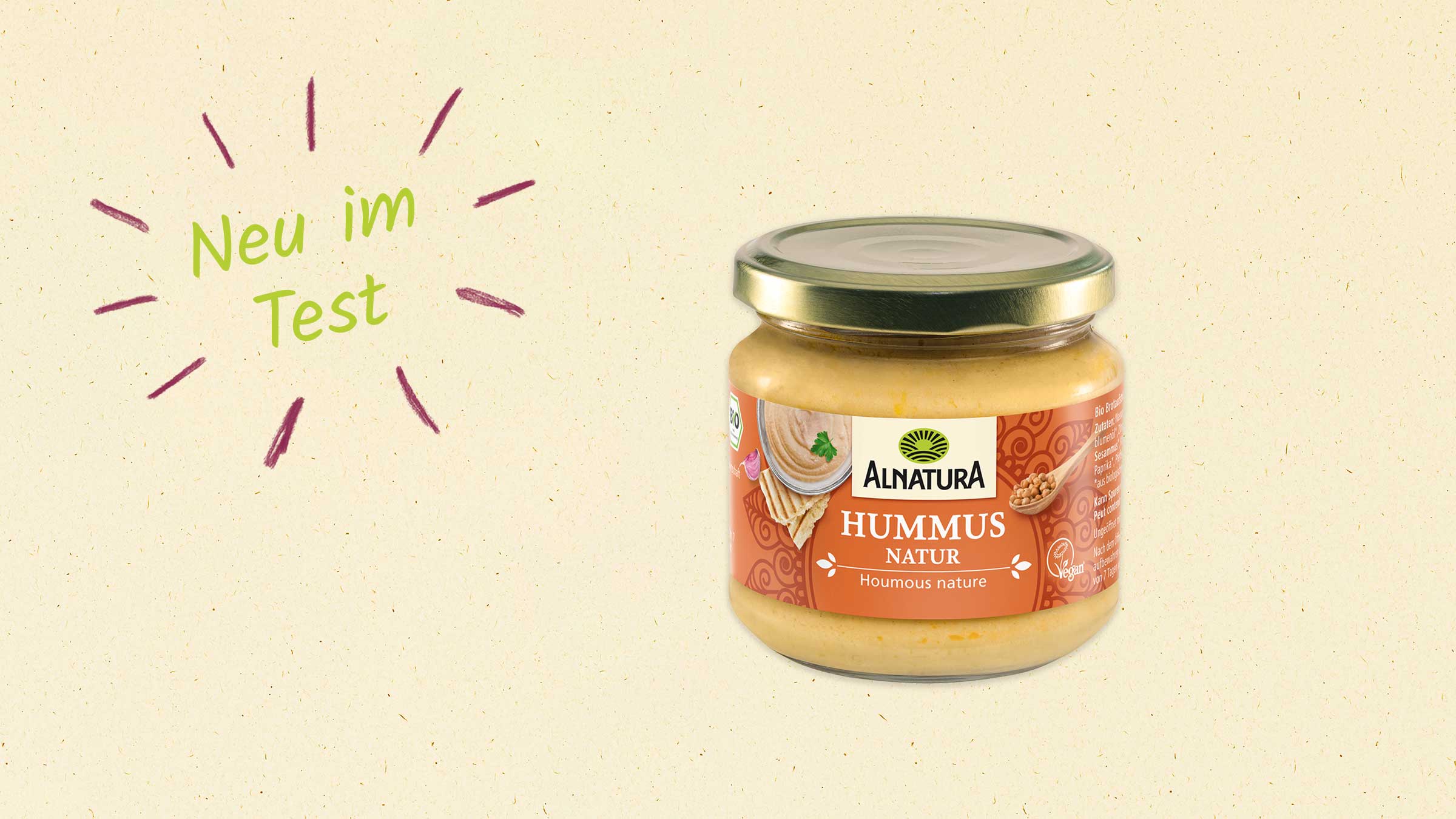 Das Bild zeigt ein Glas Alnatura Hummus Natur mit dem Text "Neu im Test" daneben.