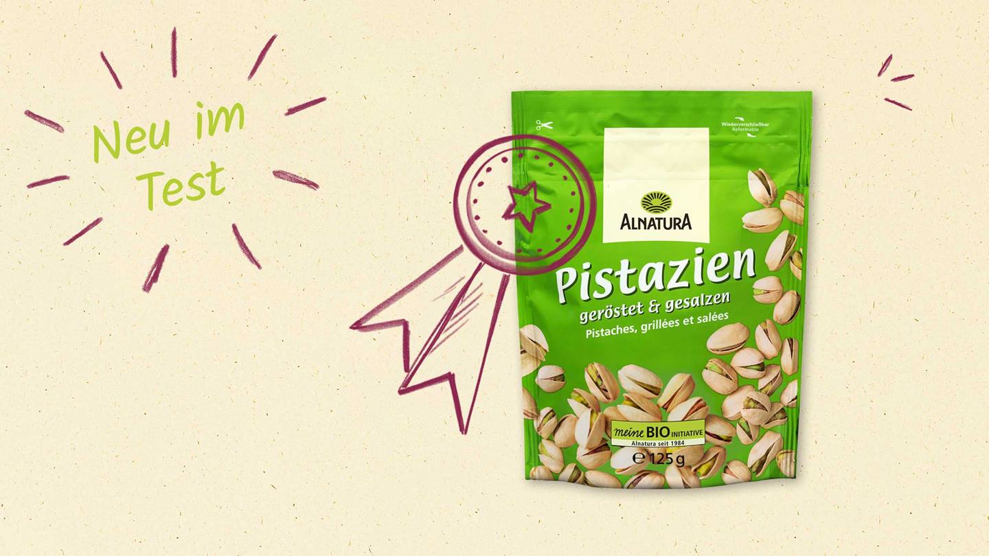 Das Bild zeigt eine Packung gerösteter und gesalzener Pistazien der Marke Alnatura. Die Packung ist grün und zeigt die Pistazien. Auf der Packung ist das Logo von Alnatura und der Hinweis "meine BIO INITIATIVE" zu sehen. Im Bild ist außerdem der Text "Neu im Test" mit einer handgezeichneten Schleife, die eine Auszeichnung symbolisiert, zu sehen. Das suggeriert, dass das Produkt getestet wurde.