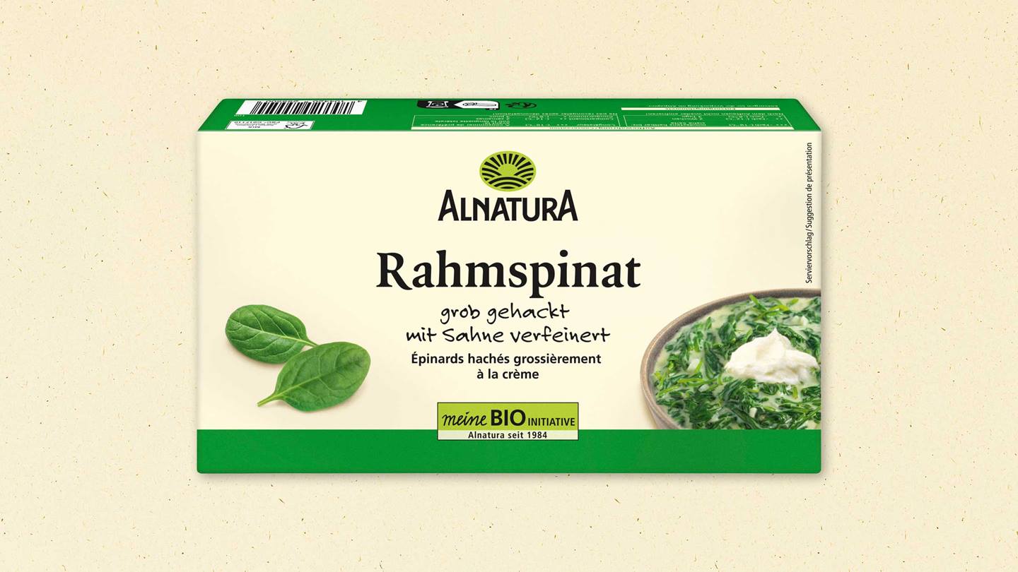 Das Bild zeigt die Verpackung von Alnatura Rahmspinat. Die Verpackung ist grün und beige und zeigt neben dem Produktnamen auch einen Serviervorschlag: grob gehackten Spinat mit Sahne, garniert mit einem Klecks Sauerrahm. Zusätzlich wird die BIO-Initiative von Alnatura hervorgehoben, sowie das Gründungsjahr 1984.