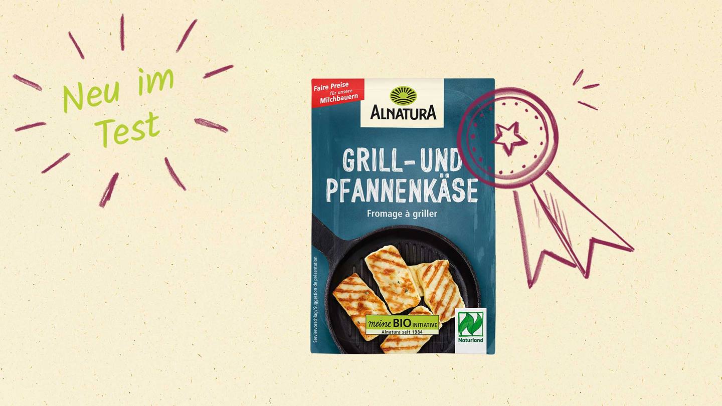 Das Bild zeigt eine Verpackung von Alnatura Grill- und Pfannenkase. Die Verpackung ist im Fokus und zeigt gegrillten Käse in einer Pfanne. Links oben steht "Neu im Test", rechts oben ist eine gezeichnete Auszeichnung. Auf der Verpackung sind die Logos von "meine BIO Initiative" und "Naturland" abgebildet.