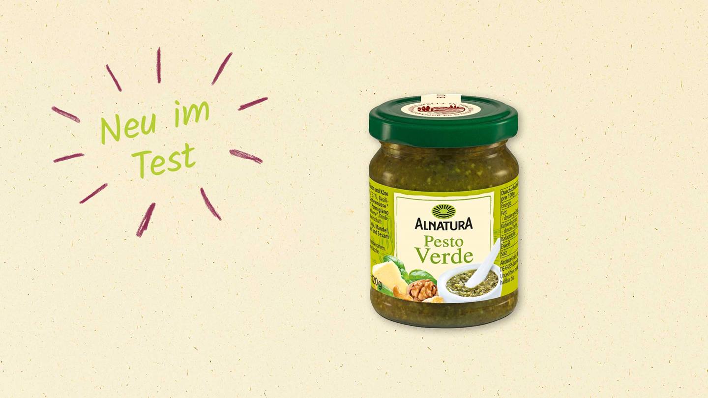 Das Bild zeigt ein Glas Alnatura Pesto Verde. Im Vordergrund steht der Hinweis "Neu im Test", handgeschrieben auf einem hellbeigefarbenen Hintergrund. Das Glas Pesto ist deutlich sichtbar und die Zutaten sowie Nährwertangaben sind lesbar. Das Bild weißt auf eine neues Testergebnis hin.