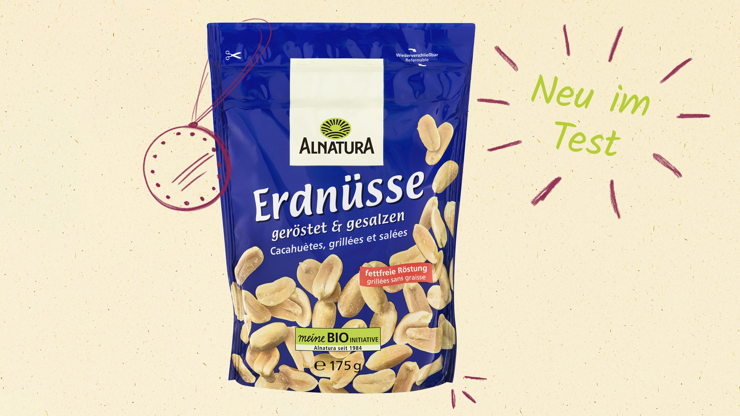 Packung "Alnatura Erdnüsse geröstet und gesalzen" auf einem hellen, strukturierten Hintergrund. Rechts ist ein grüner Schriftzug "Neu im Test" mit umgebenden Strichen in roter Farbe zu sehen. 