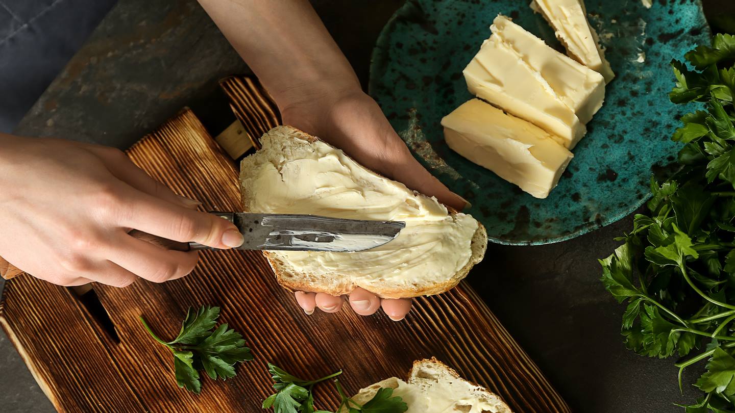Butter wird mit einem Messer auf ein Brot gestrichen