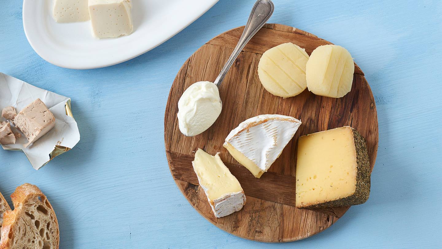 Verschiedene Käsesorten (Harzer, Camembert, Frischkäse, Stück-Käse) auf einem Holzteller