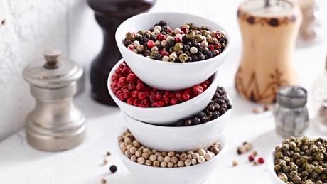 Verschiedene Pfeffersorten: schwarzer Pfeffer, weißer Pfeffer, grüner Pfeffer und rote Pfefferbeeren