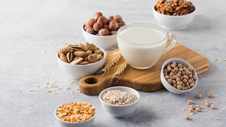 Laktosefreie Milch im Glas und Haferflocken und Nüsse in Schälchen