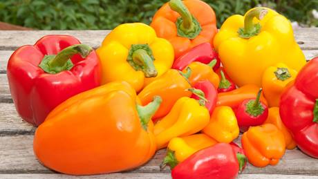 Rote, gelbe und orangene Paprikaschoten auf einem Tisch liegend