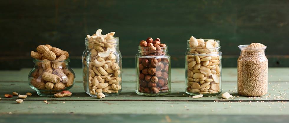 verschiedene Nüsse in Gläsern: Erdnüsse, Cashewkerne, Mandeln, Haselnüsse
