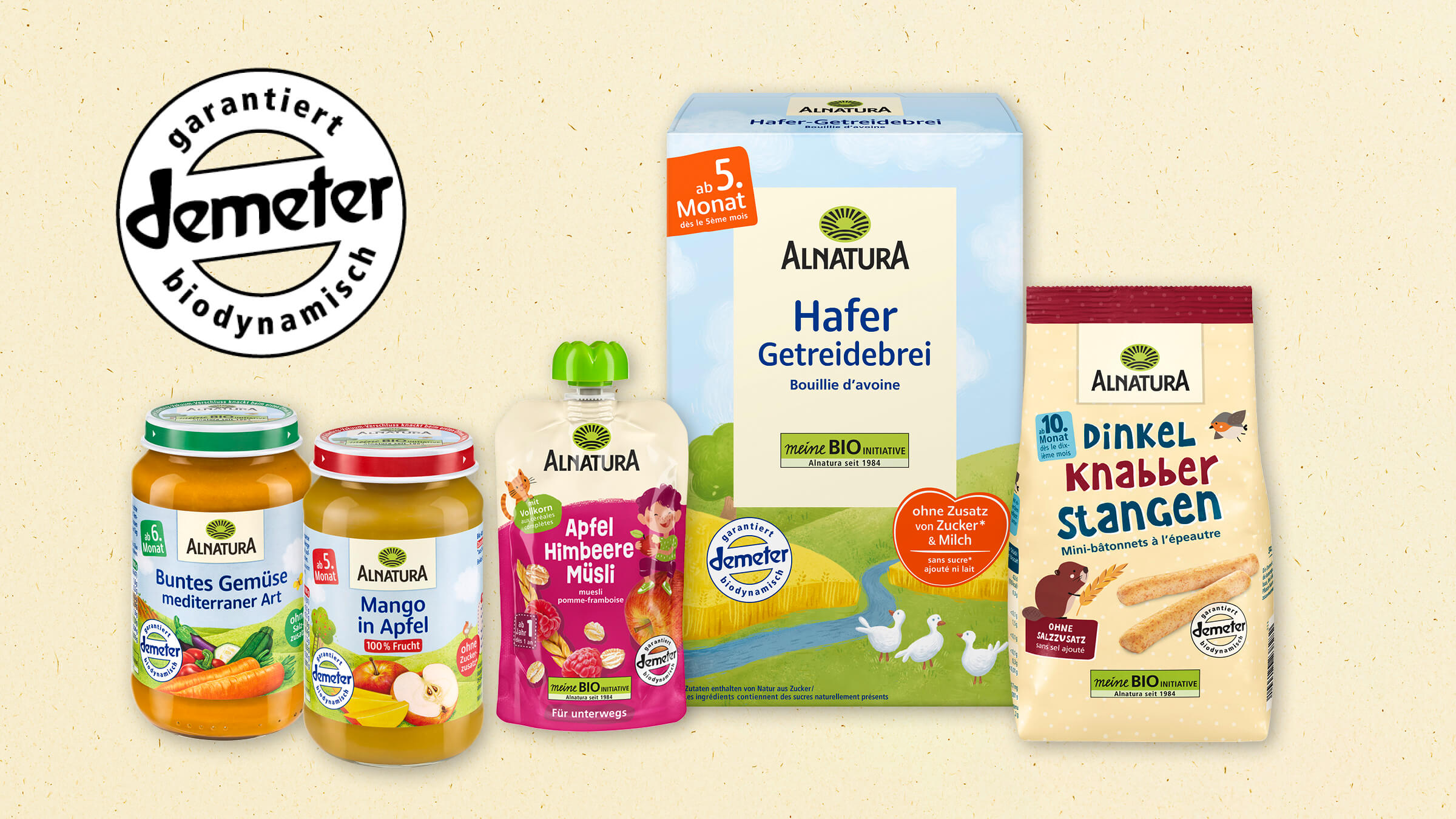 Die Abbildung zeigt eine Auswahl an Baby- und Kleinkindnahrungsprodukten der Marke Alnatura, die alle das demeter-Siegel tragen. Es ist ein Quetschbeutel Sorte Apfel-Himbeeren-Müsli, zwei Babygläschen mit Gemüse und Obst, eine Packung Hafer-Getreidebrei und eine Tüte Dinkel-Knabberstangen.