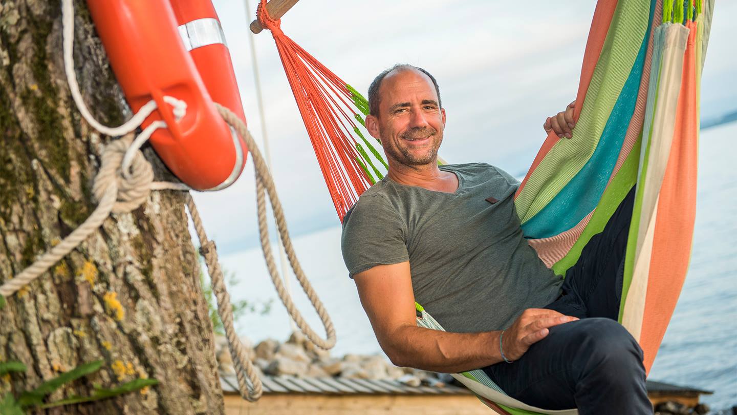 Geschäftsführer Jürg Knoll sitzt in einer Hängematte  am Ufer