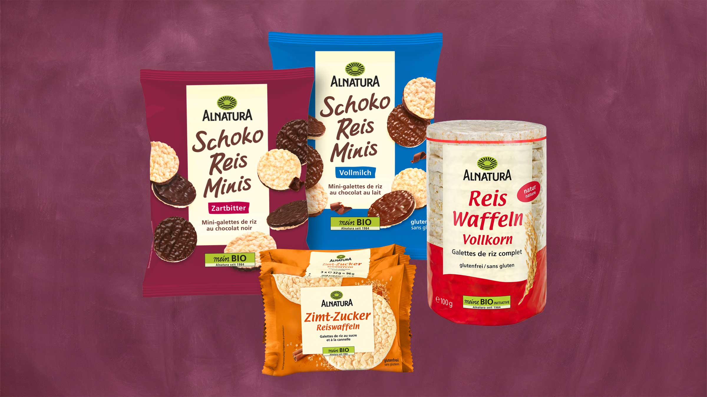 Auf dem Bild sind 4 Packungen verschiedene Reiswaffeln zu sehen: Reiswaffeln Vollkorn, Schoko Reisminis Vollmilch, Schoko Reisminis Zartbitte und Zimt-Zucker Reiswaffeln. Der Hintergrund ist violett.
