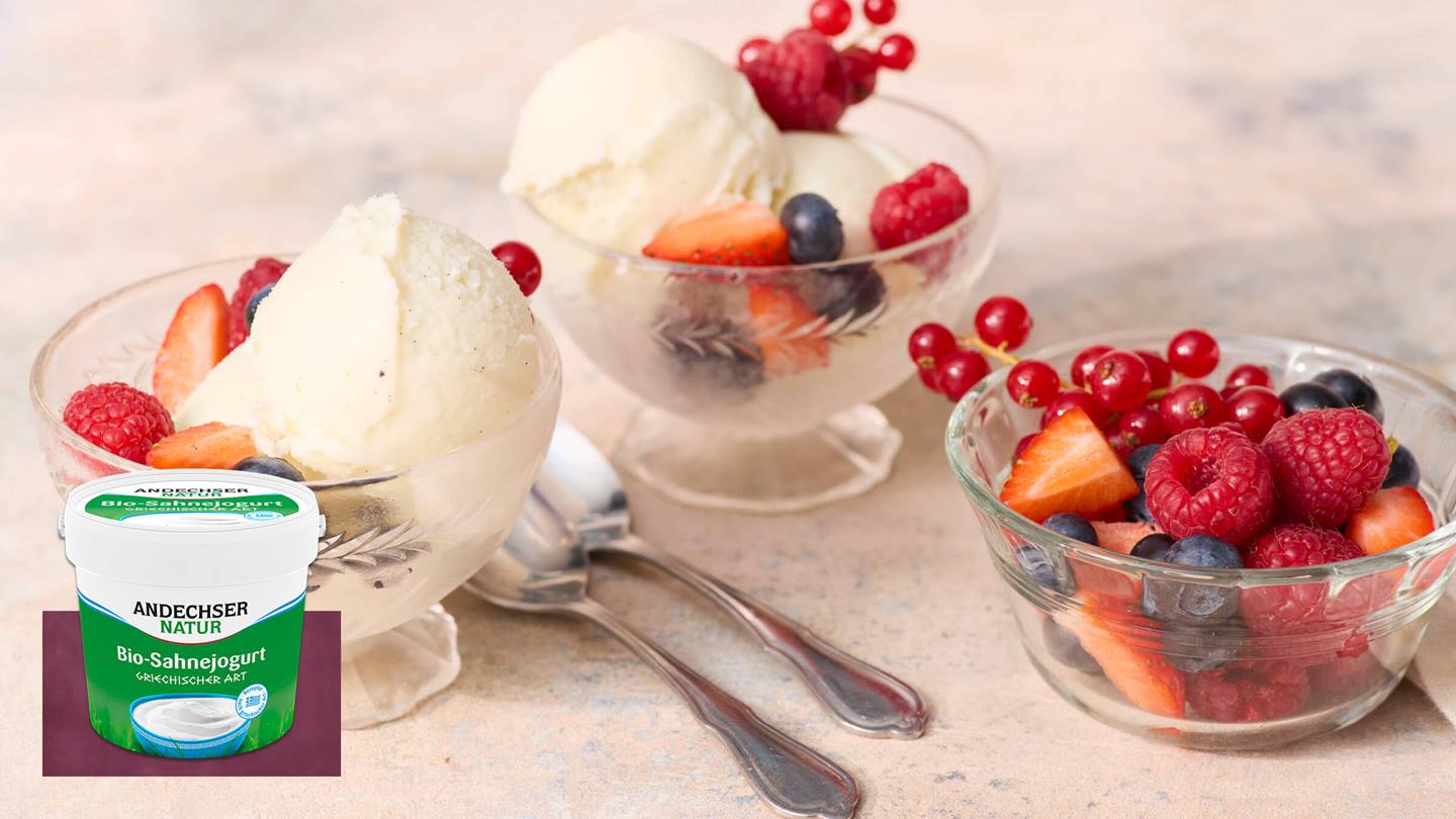 Schalen mit Eiscreme und Beeren, daneben ein Becher Joghurt.