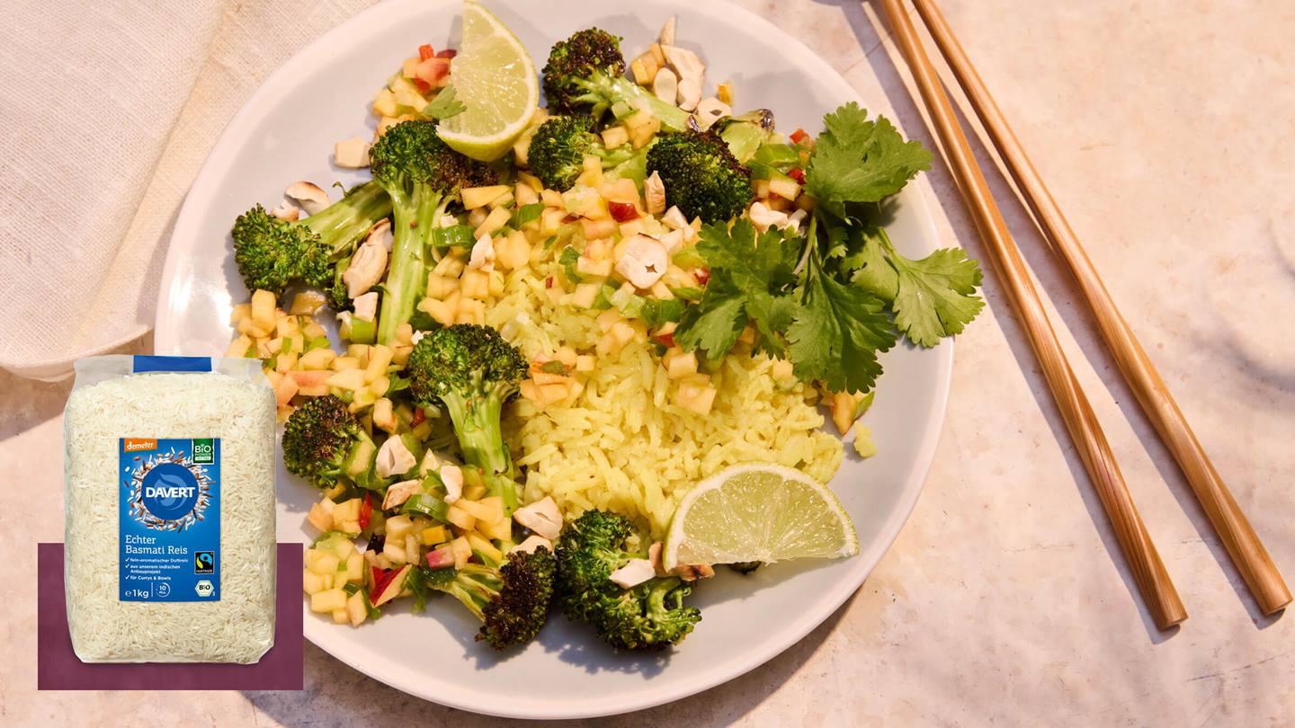 Teller mit Reis, Brokkoli, gehackten Nüssen, Limettenscheiben und Korianderzweigen neben einer Packung Davert Bio Basmati Reis und Essstäbchen