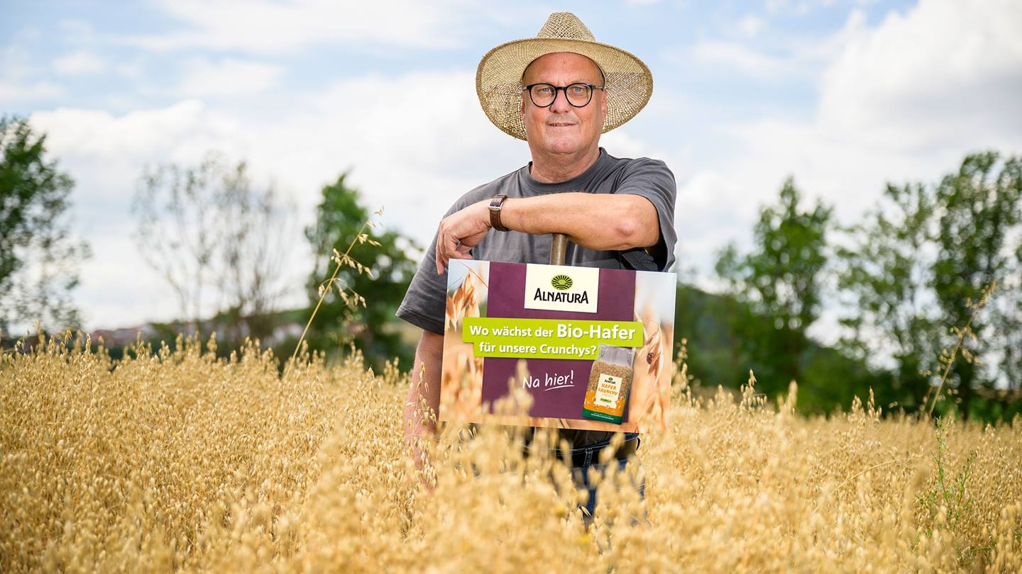 Landwirt Hoffmann in seinem Bio-Haferfeld mit einem Alnatura Schild