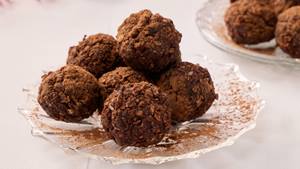 Auf einem kleinen Glastellerchen liegen mehrere dunkle Kugeln gestapelt. Im Hintergrund steht ein weiteres Glastellerchen mit weiteren Kugeln.