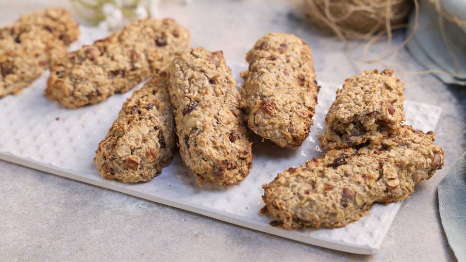 Gebackene Stangen aus Müsli liegen auf einem weißen geriffelten Brett