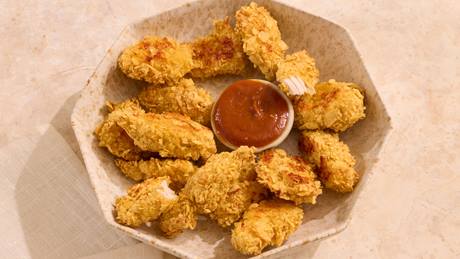 Schale mit panierten Chicken Nuggets und einer kleinen Schale mit roter Sauce in der Mitte.