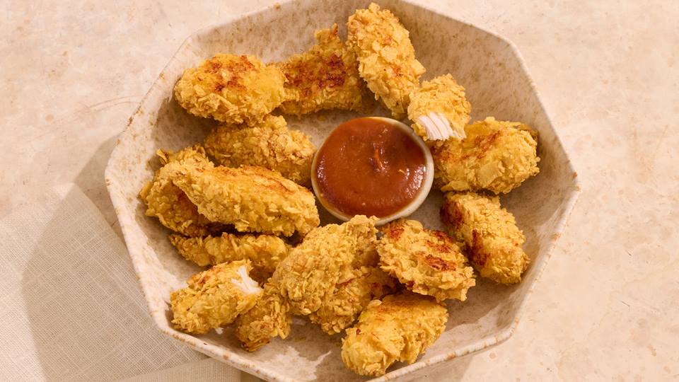 Schale mit panierten Chicken Nuggets und einer kleinen Schale mit roter Sauce in der Mitte.