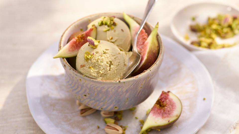 Eine Schale Pistazieneis mit Feigenstücken und gehackten Pistazien.