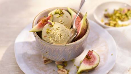 Eine Schale Pistazieneis mit Feigenstücken und gehackten Pistazien.