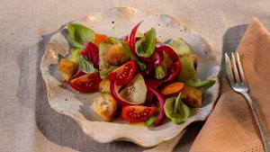 Panzanella-Salat mit geröstetem Brot, Tomaten, Gurken, roten Zwiebeln und Basilikum auf einem Teller.