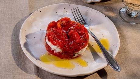 Burrata mit Tomaten und Olivenöl auf einem Teller, dazu geröstetes Brot und ein Glas Wein