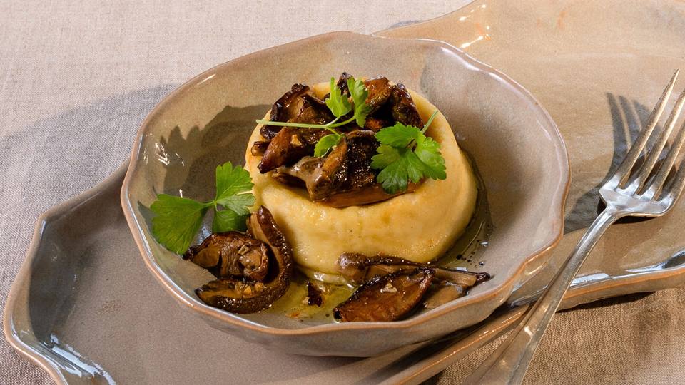 Parmigiano-Flan mit Steinpilzen und Petersilie in einer braunen Porzellan-Schüssel, daneben eine Gabel