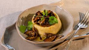 Parmigiano-Flan mit Steinpilzen und Petersilie in einer braunen Porzellan-Schüssel, daneben eine Gabel