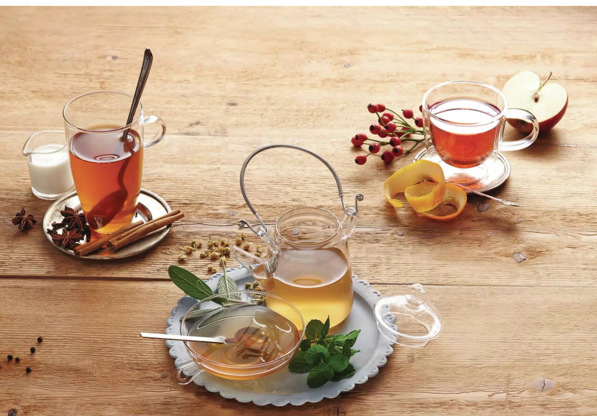 Verschiedene Kräuter oder Früchtetees in Glastassen. Tees mit Minze, Salbei, Zimt, Nelken, Hagebutte Apfel und Orangen.