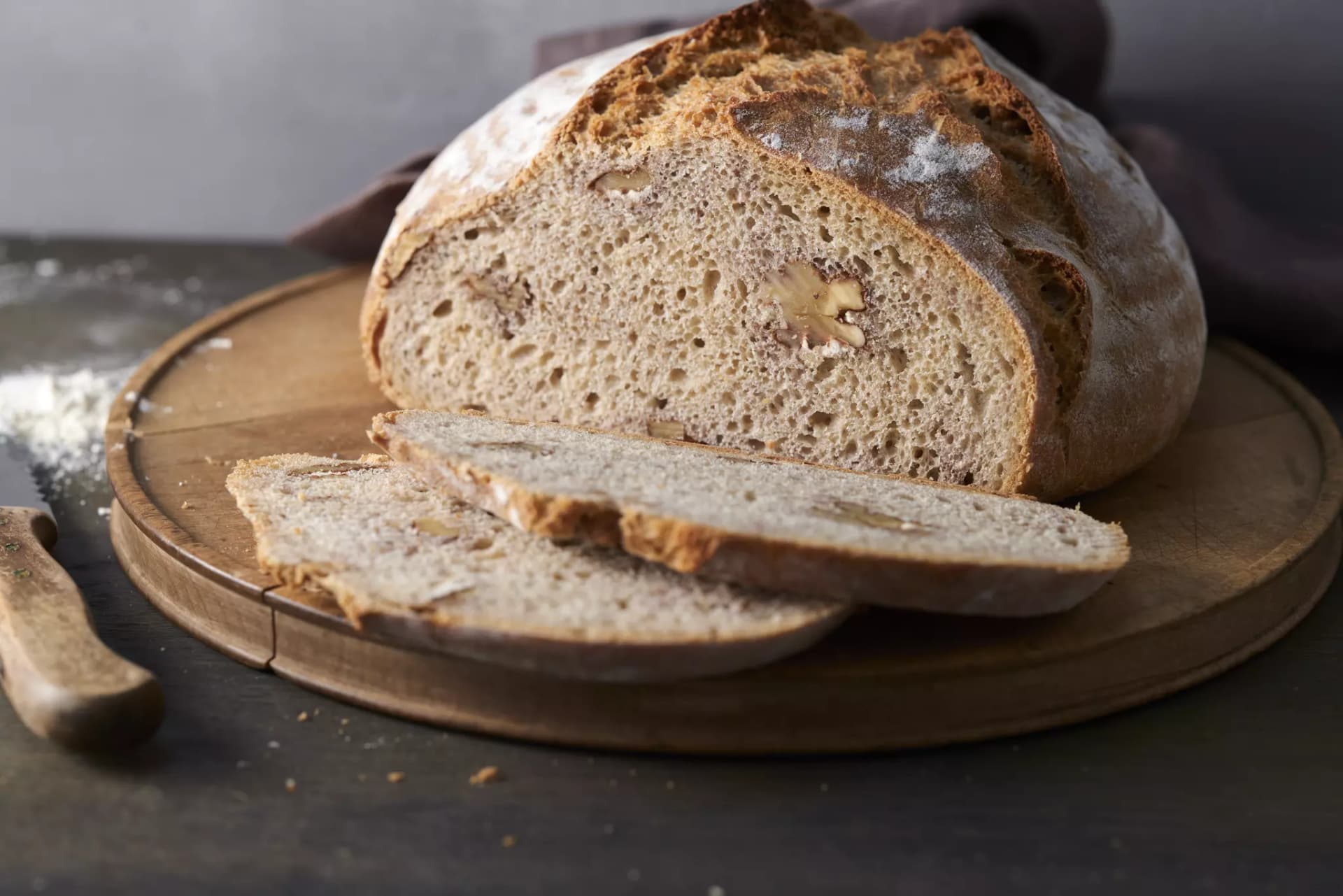 Aufgeschnittenes rundes Brot mit Walnussstücken auf einem Holzbrett