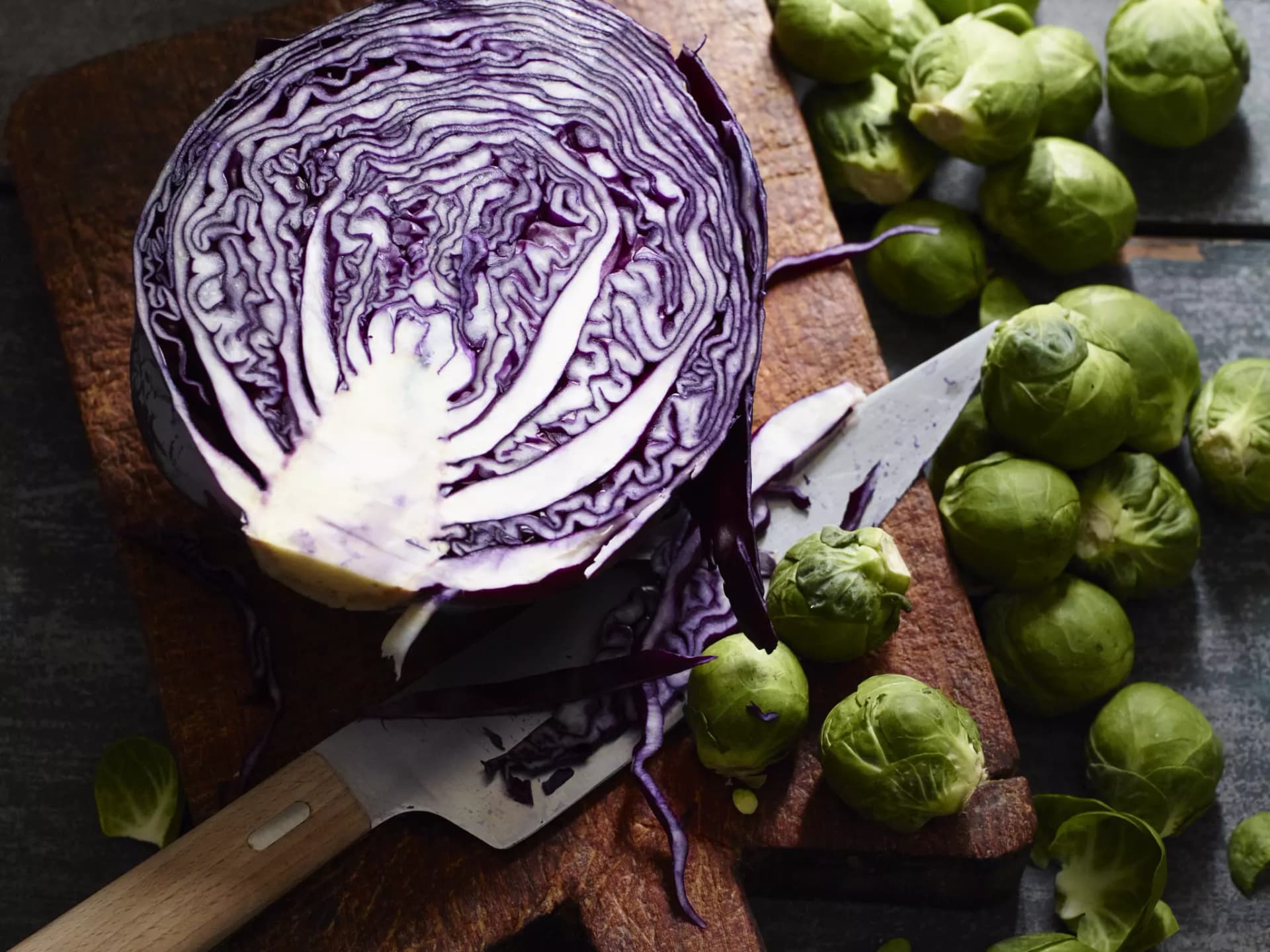 Warenkunde Kohl. Aufgeschnittener, halber Rotkohl, daneben Rosenkohl