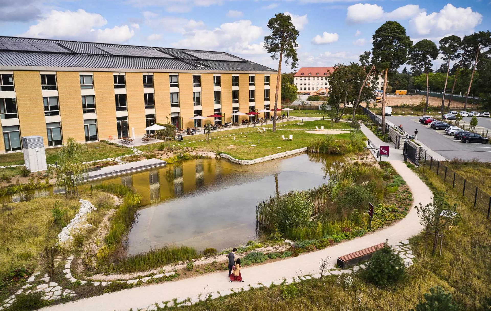 Seitliche Aussenansicht des Alnatura Campus mit Teich und Terrasse des Restaurants