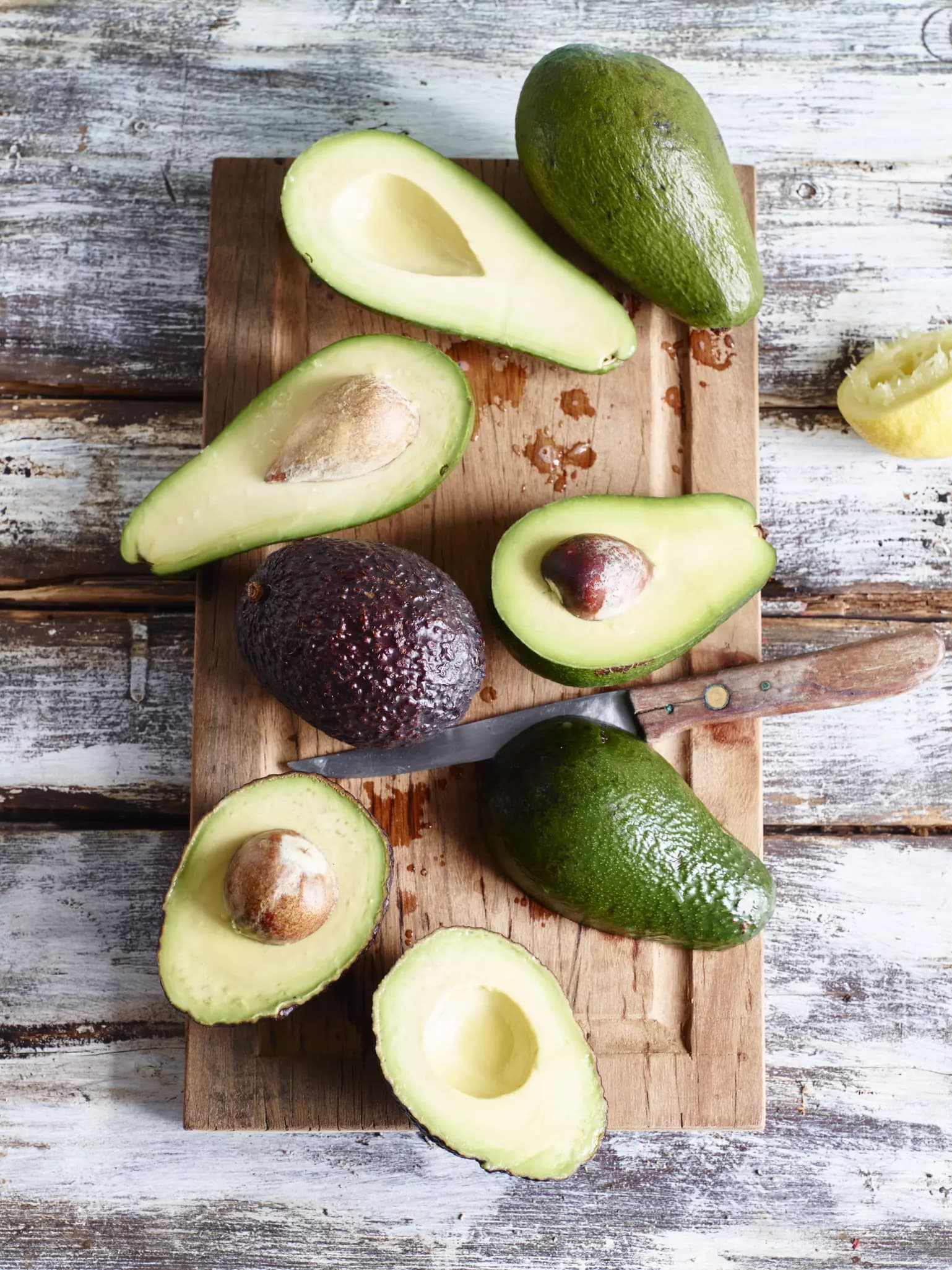Fünf verschiedene Avocado-Sorten, drei aufgeschnitten mit sichtbarem Kern.