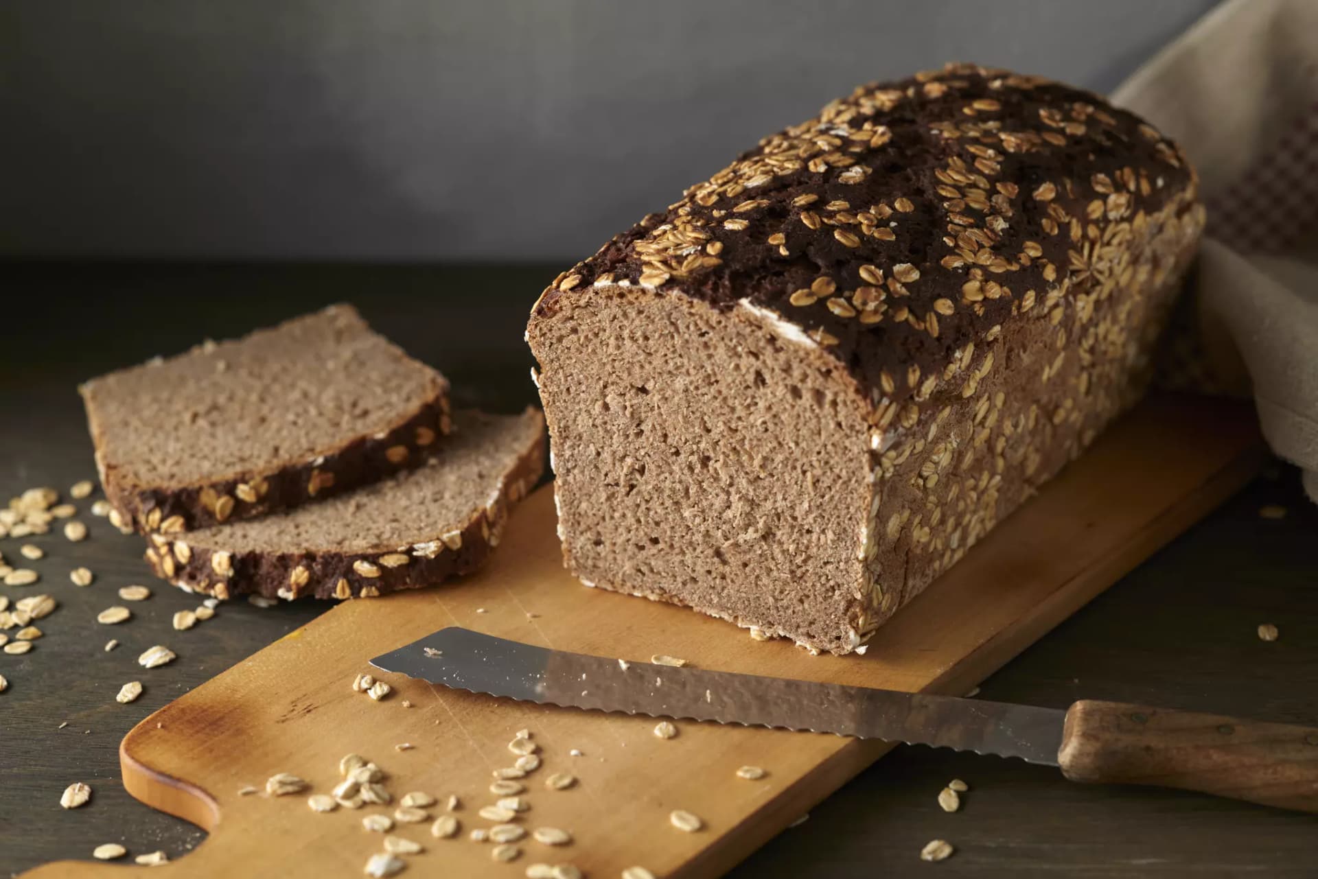 Roggensauerteigbrot in Kastenform, auf Holzbrett mit zwei aufgeschnittenen Scheiben
