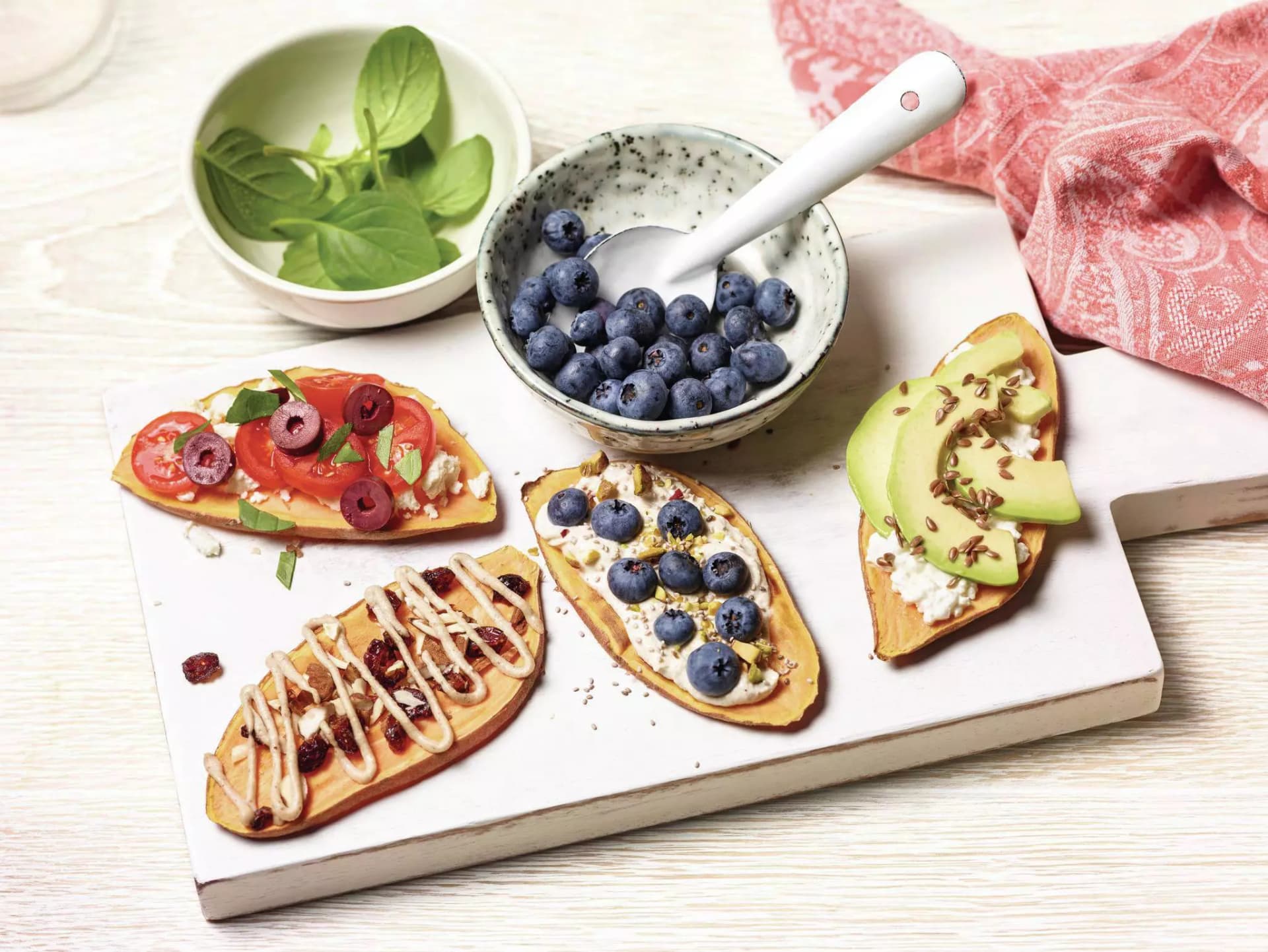 Getoastete Süßkartoffel Scheiben mit Avocado-, Tomaten-, und Heidelbeeren Belag.
