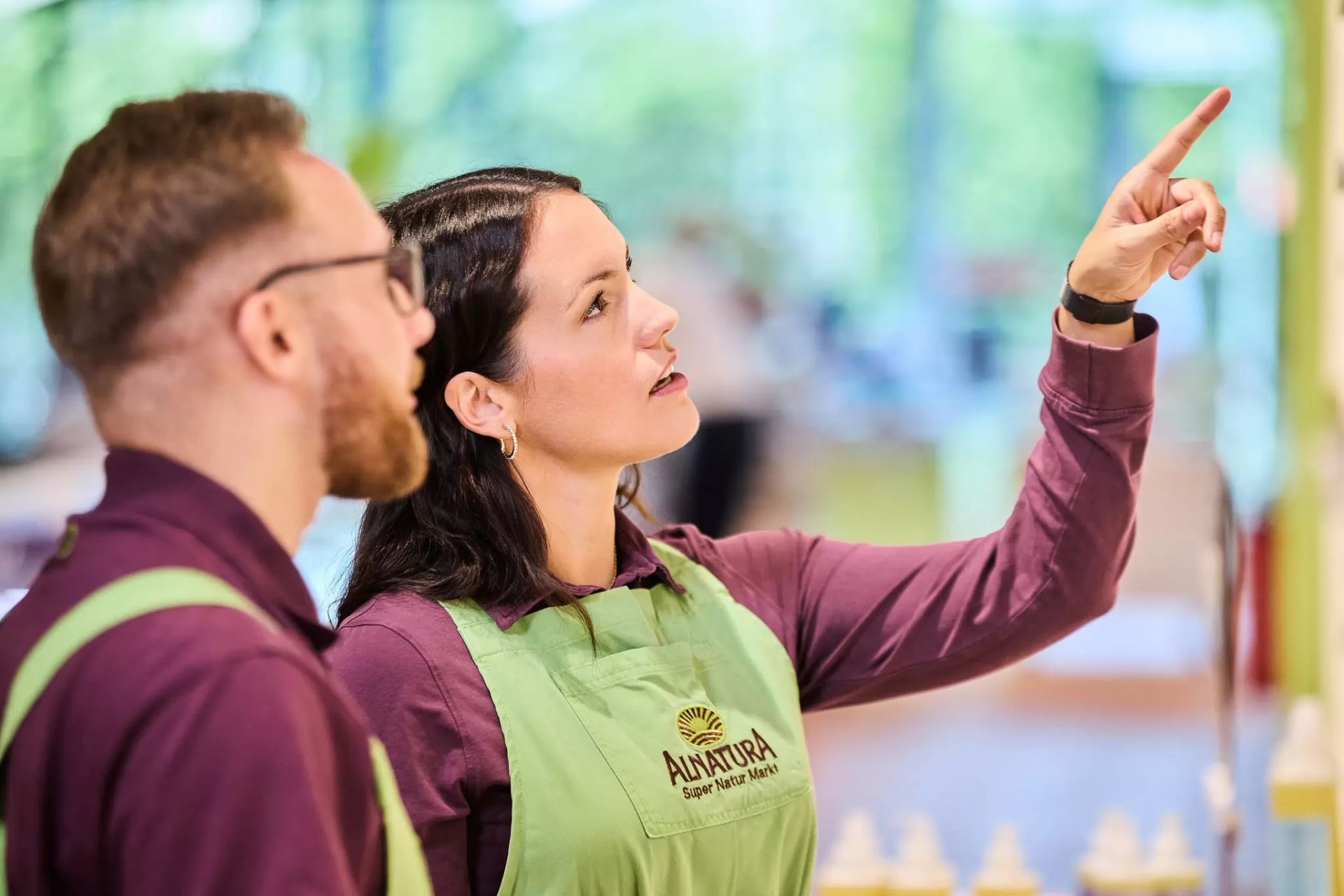 Zwei Alnatura Mitarbeitende betrachten im Marktregal ein Produkt.