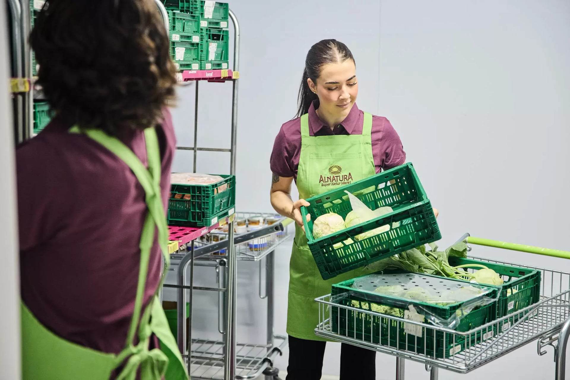 Zwei Alnatura Mitarbeitende stehen vor dem Warenregal und begutachten die Produkte