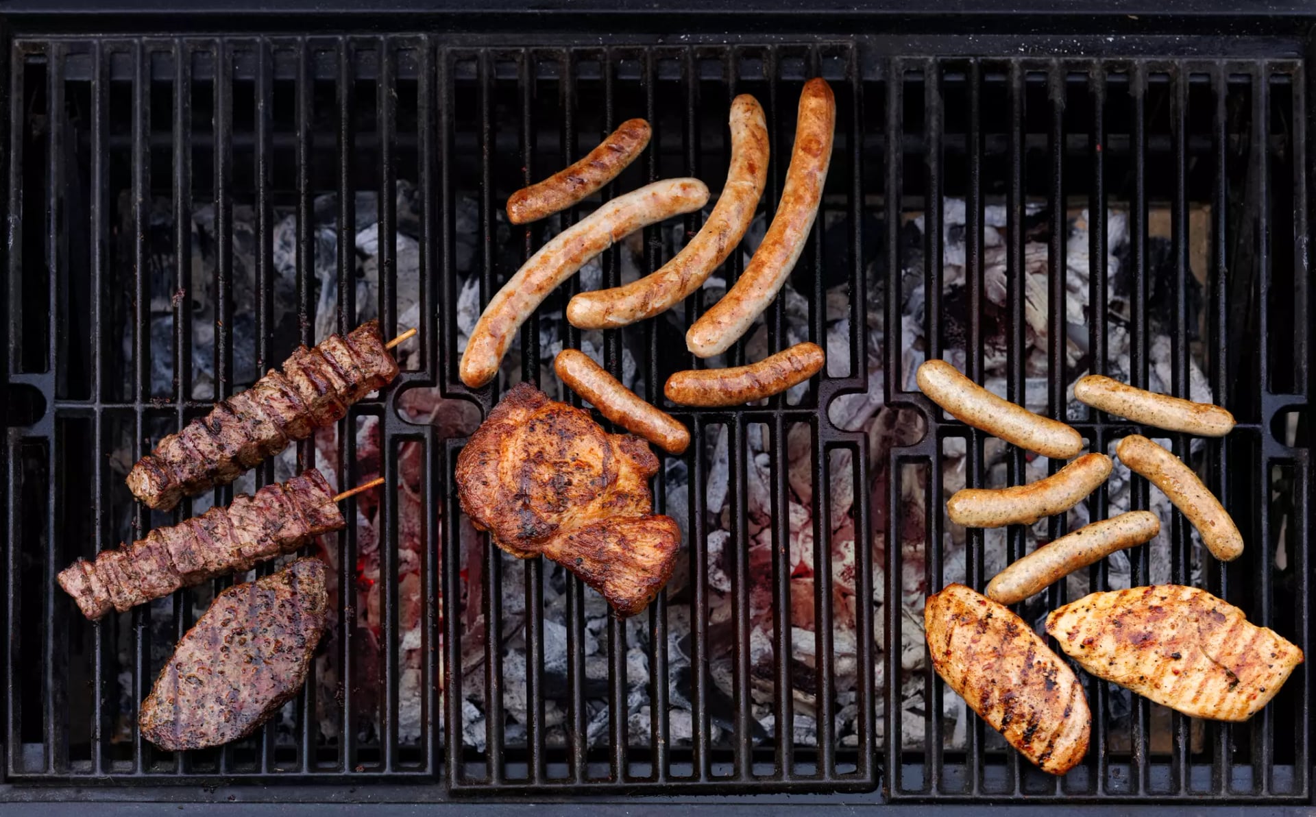 Verschiedene Sorten Fleisch und Würsten auf dem Grillrost