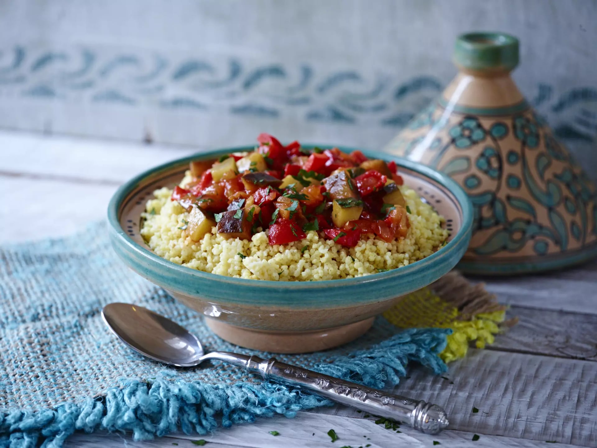 Hirse-Gemüse-Gericht in einer orientalischen Tajine auf einem blauen Tuch.
