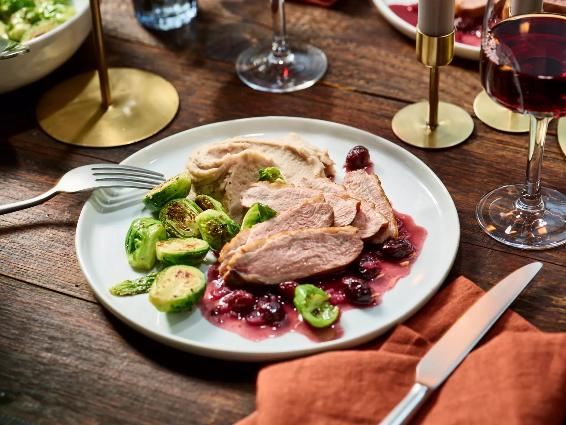 Gänsebrust mit Cranberry Sauce und Rosenkohl angerichtet auf einem Teller.
