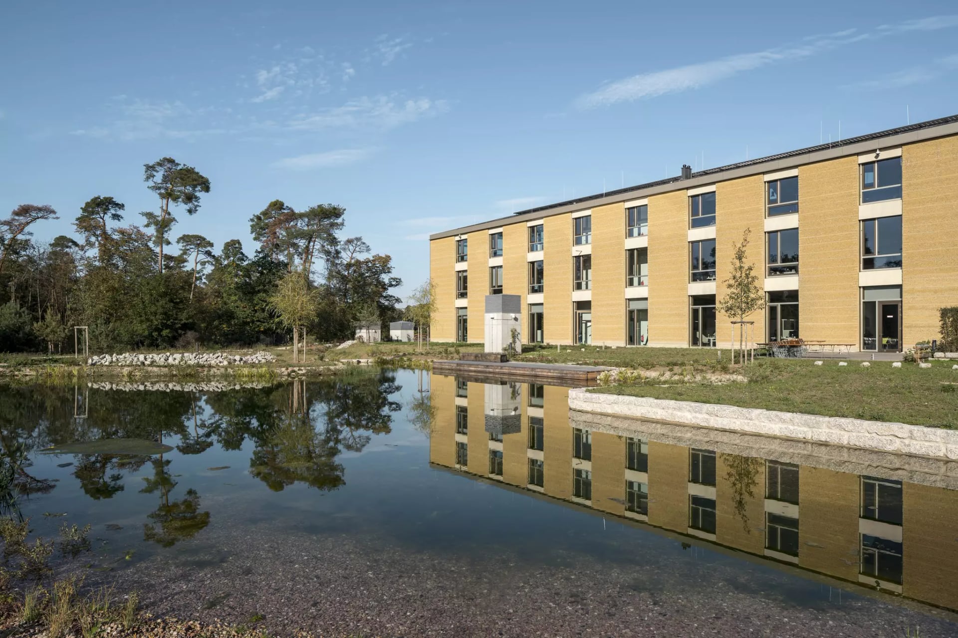 Außenansicht vom Alnatura Campus mit dem See im Vordergrund.