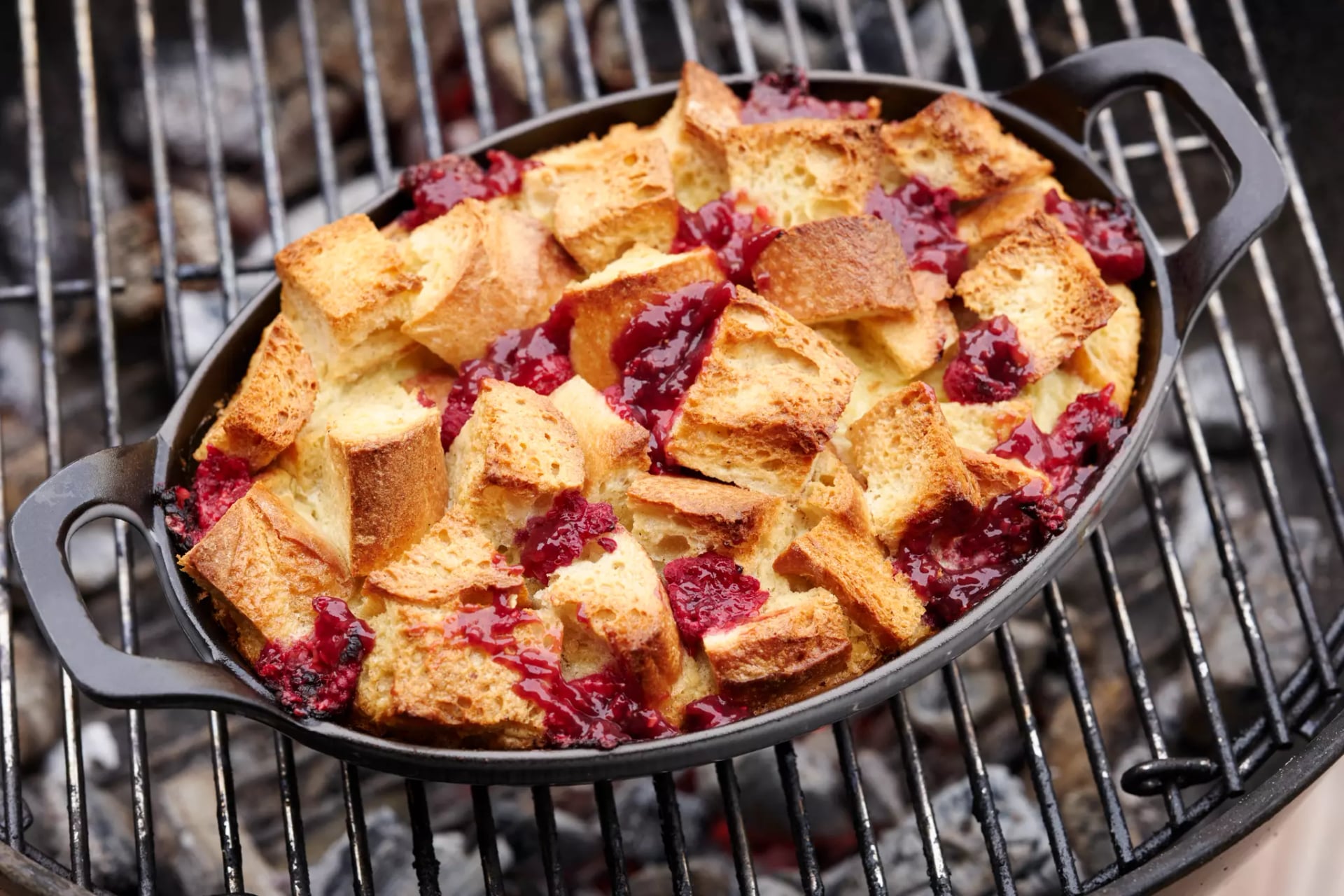 In einer gusseisernen Pfanne wird ein Auflauf aus Baguette-Stücken und Himbeeren gegrillt.
