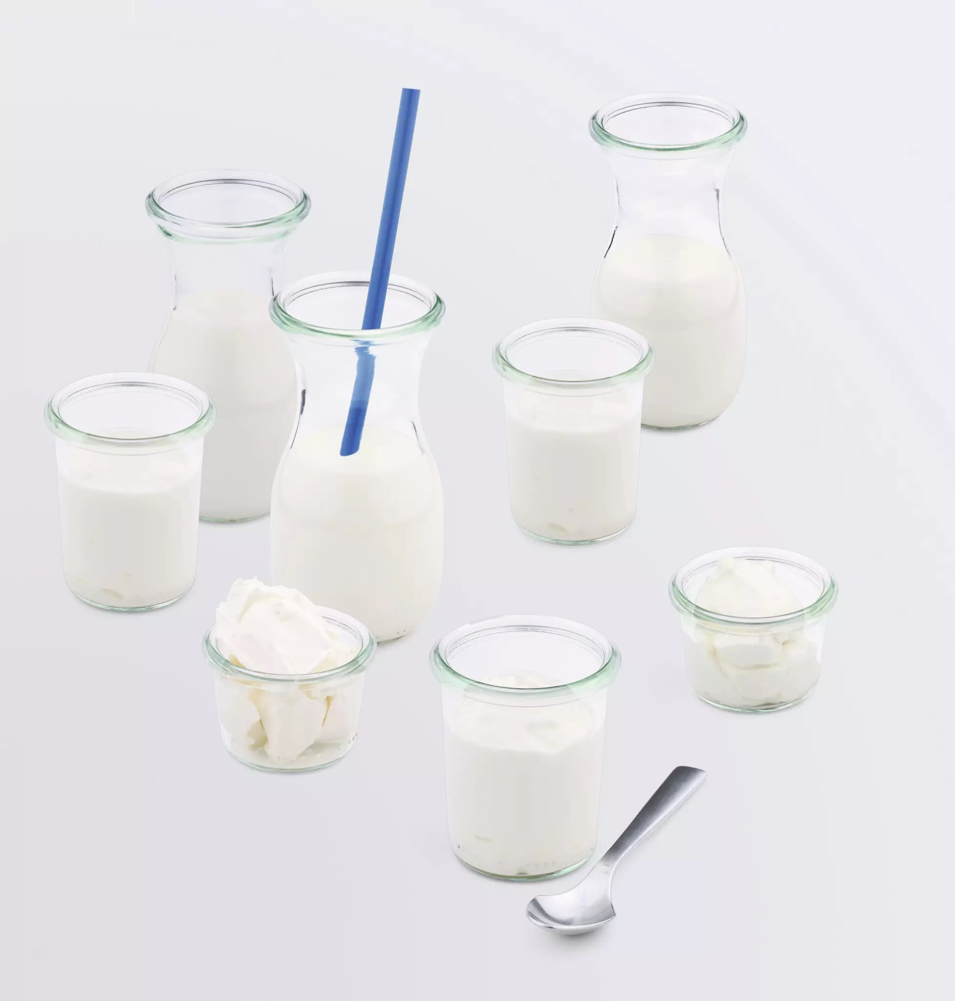 Gläser und Karaffen gefüllt mit Milch vor einem weißen Hintergrund
