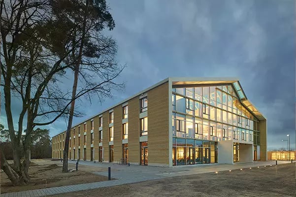 Außenansicht des Alnatura Campus am Abend mit dunklem Himmel und beleuchteten Bürogebäude
