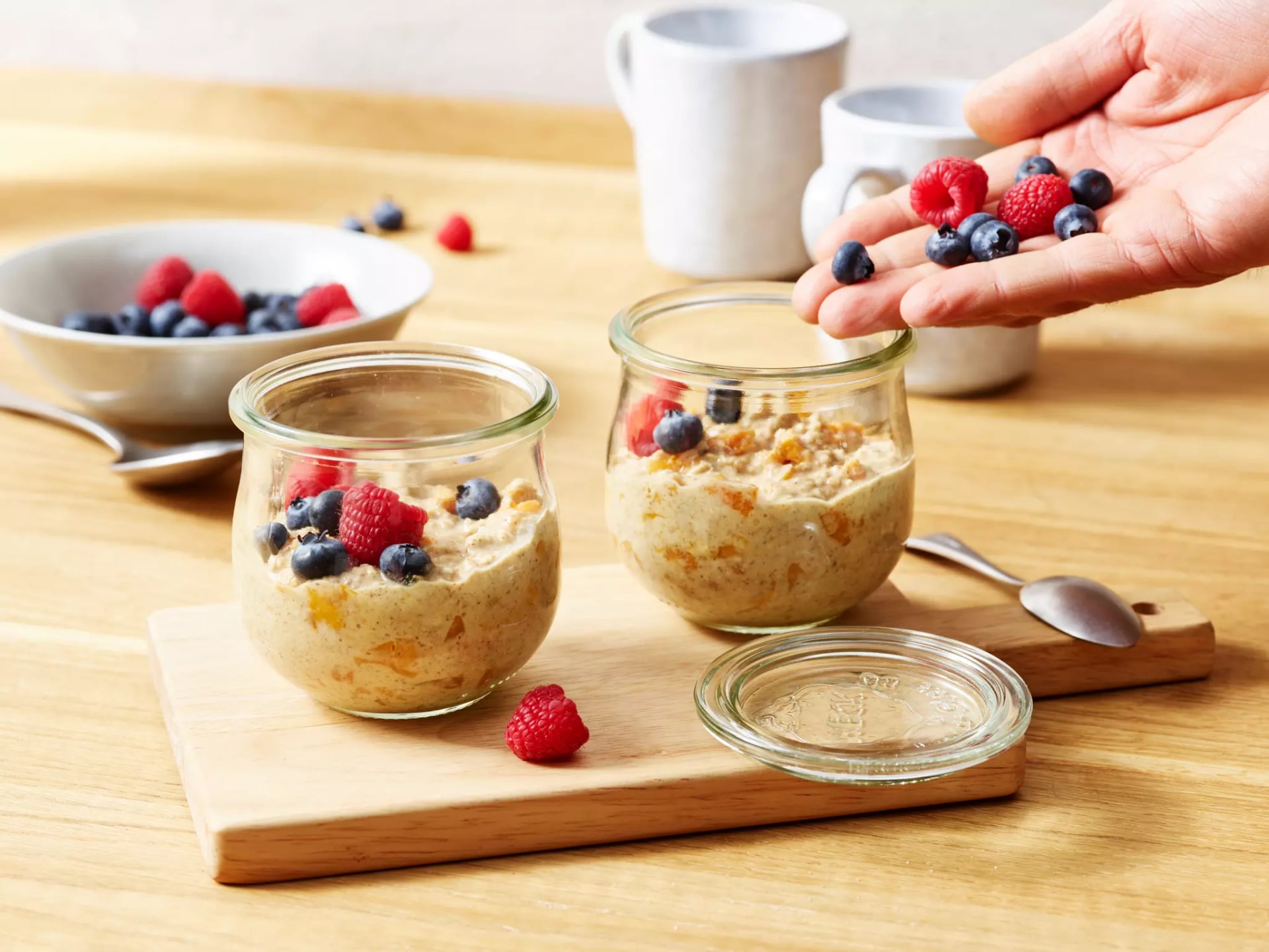 Zwei Gläser mit Overnight-Oats mit Himbeeren und Heidelbeeren