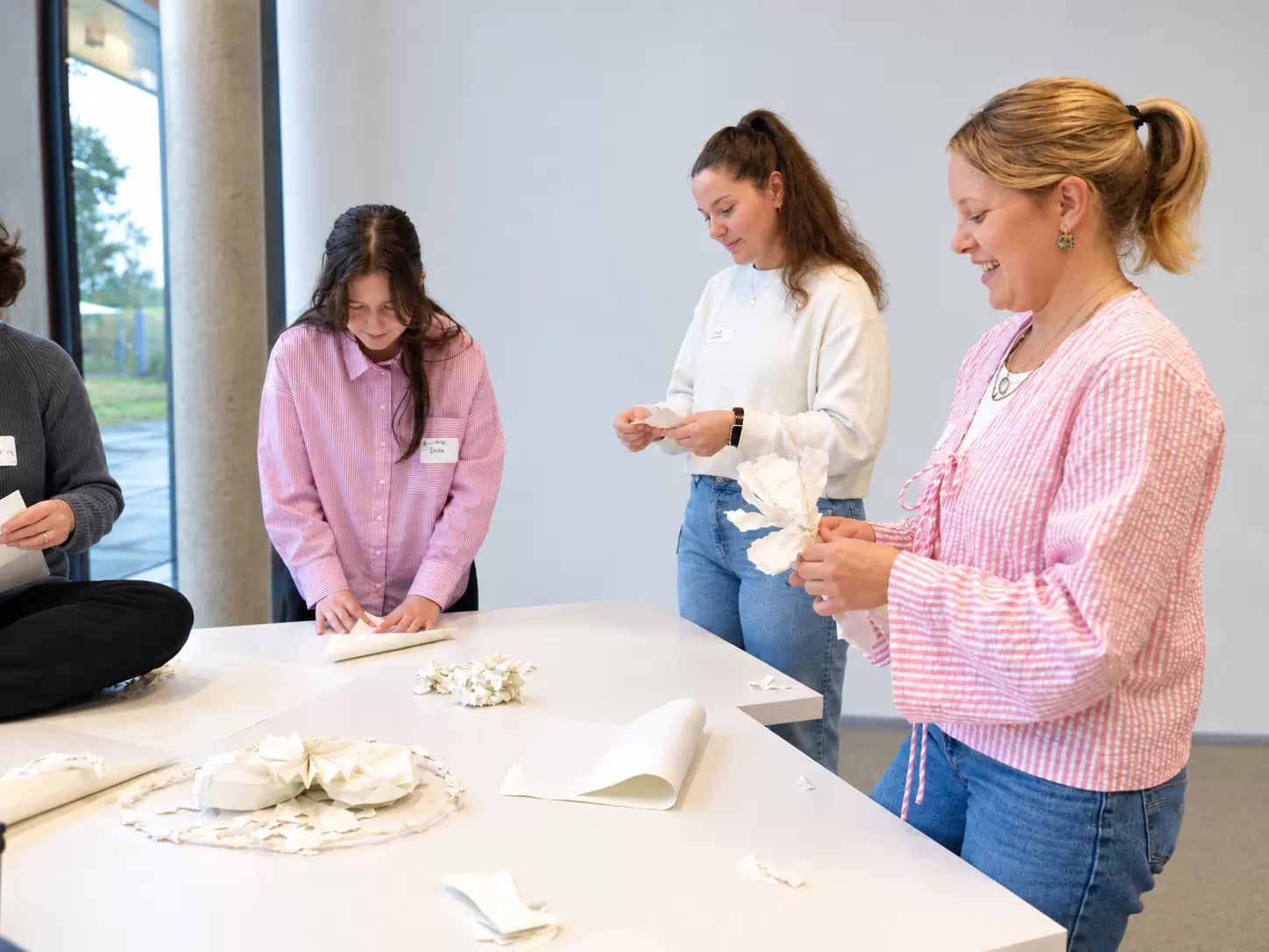 Frauen stehen an einem Tisch und falten Papier
